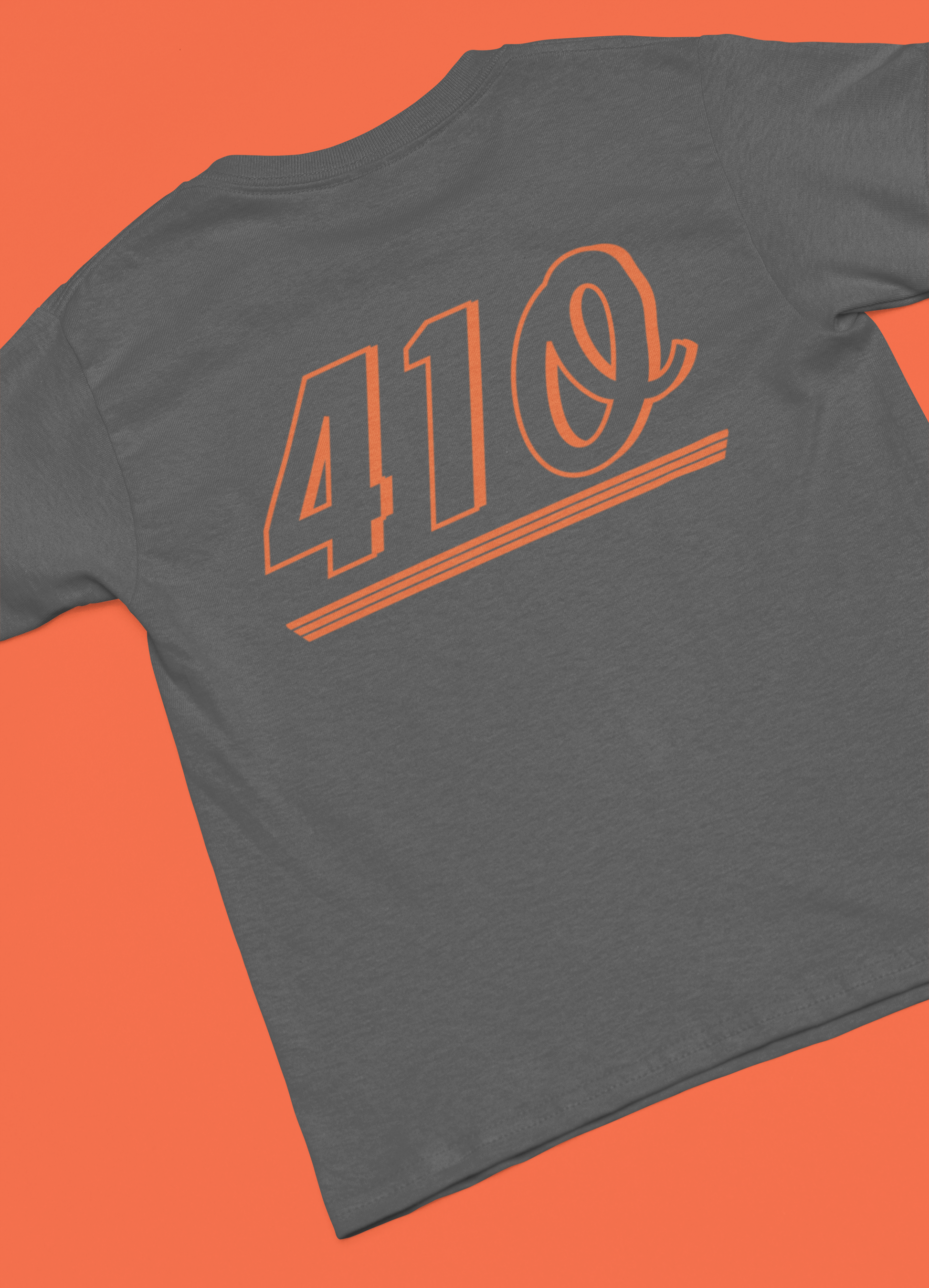 This is a T-shirt that is dark grey, and the shirt is laying flat and unfolded. This shirt has a design on it that is orange in color. The design says 410, which is an ode to the area code of Baltimore. The design on the shirt is about 10 inches wide, and about 6 inches long. 